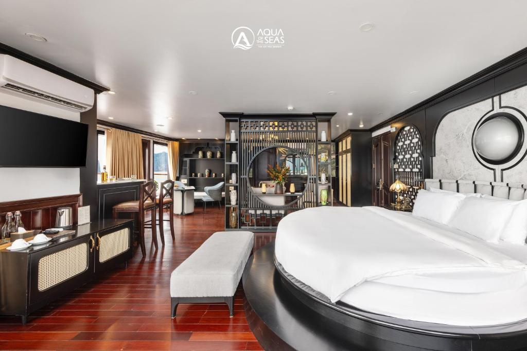 a bedroom with a large bed and a living room at Aqua of the Seas Cruise in Ha Long