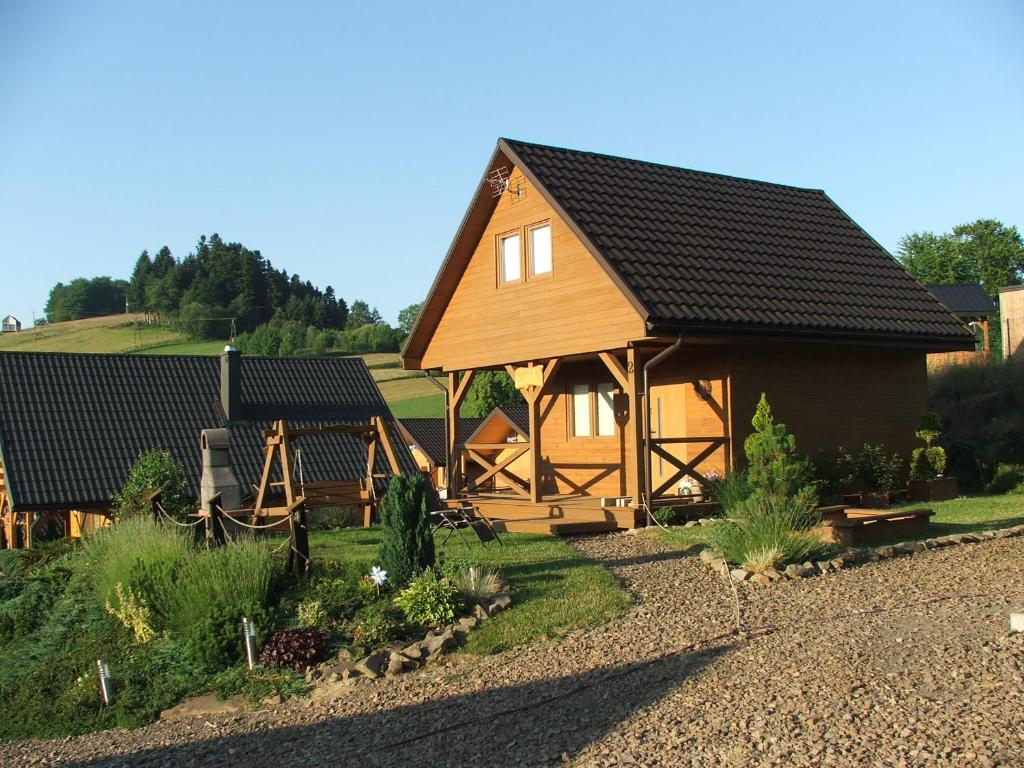 a large wooden house with a black roof at Domki Lawendowa Skarpa in Zawóz