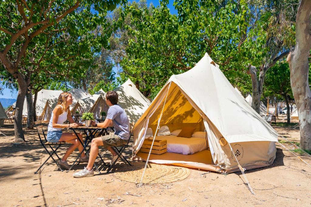a man and woman sitting at a table in front of a tent at Kampaoh Delta del Ebro in Poblenou del Delta