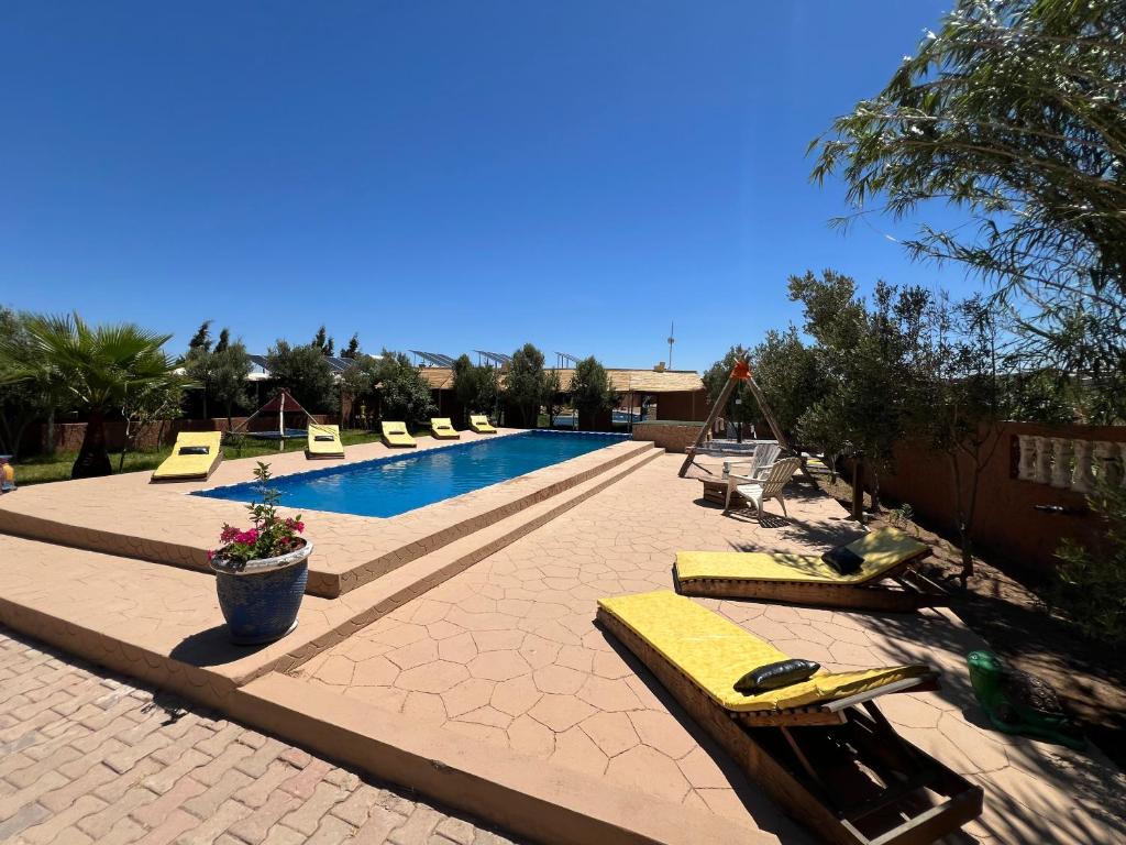 a swimming pool with yellow lounge chairs and a swimming pool at auberge Brava Tifnit in El Azib