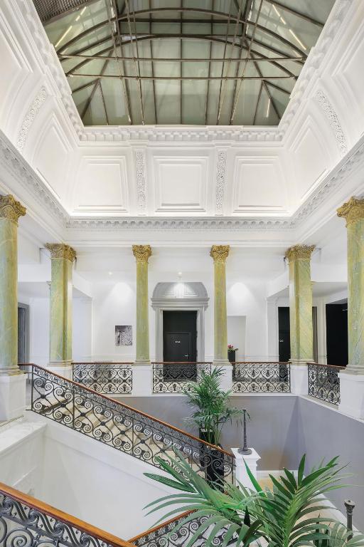 a large white room with a ceiling with columns at Appart'City Collection Nîmes Arènes in Nîmes