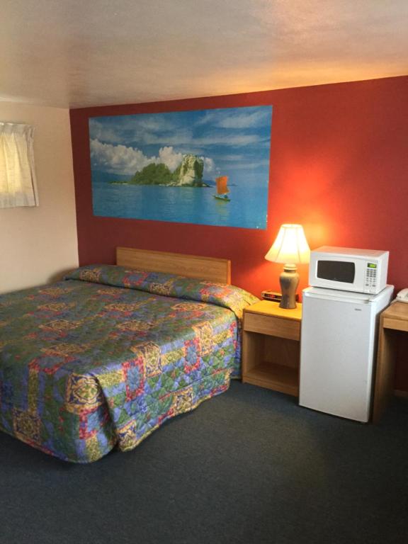 a hotel room with a bed and a microwave at Parkway Motel in Neenah