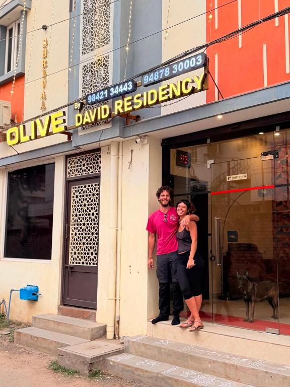 a man and a woman standing outside of a building at Olive By David Residency - Just 4 Kms from Meenakshi Amman Temple in Madurai