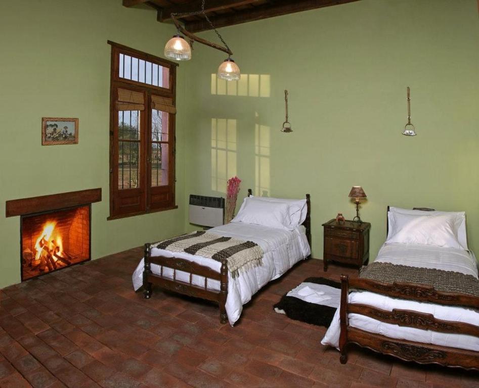 a bedroom with two beds and a fireplace at La Negrita Casa de Campo in Azcuénaga