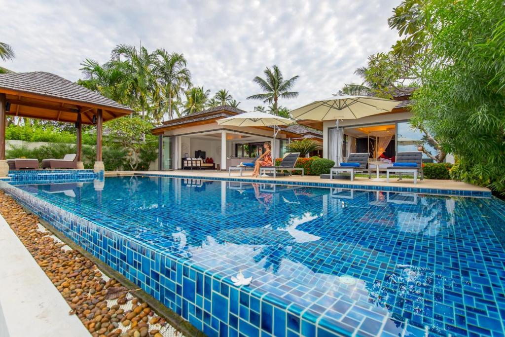 a swimming pool in front of a villa at Dhevatara Residence Beachfront Villas in Mae Nam