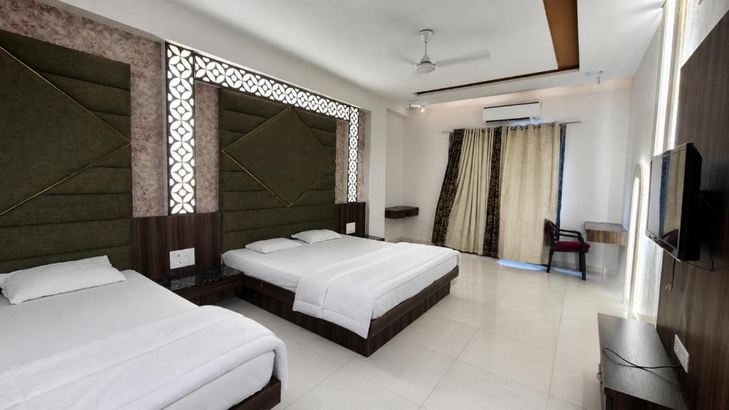 a hotel room with two beds and a television at Star resort in Bhusāwal