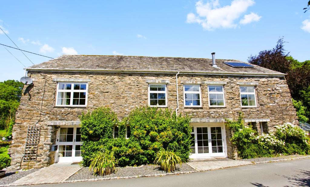a stone house with white windows on a street at Charcoal House in Coniston