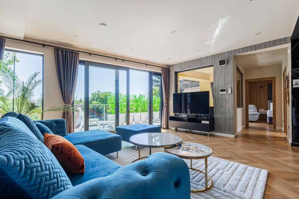 a living room with a blue couch and a tv at Elite House Gold Apartment in Leányfalu