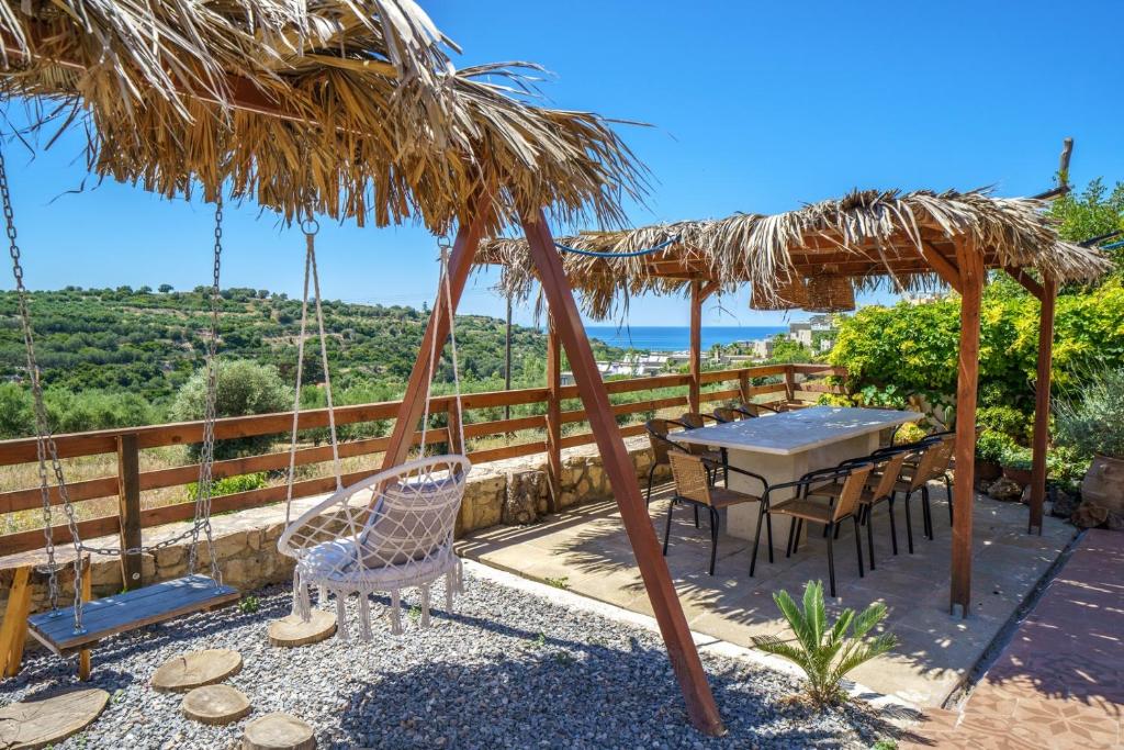 a patio with a table and chairs under a straw umbrella at Fisi & Wellness Exclusive Villa with Spa Vibes in Stavromenos