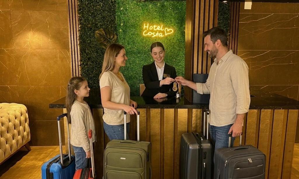a group of people standing at a bar with luggage at Aparthotel costa in Makhinjauri