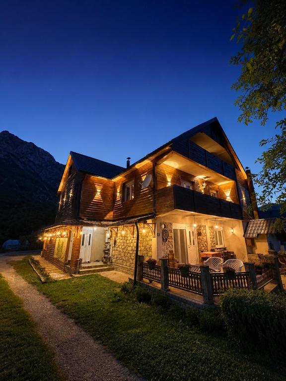 a large wooden house with lights on it at night at Riverside - Mountain Stay with Sauna in Vusanje