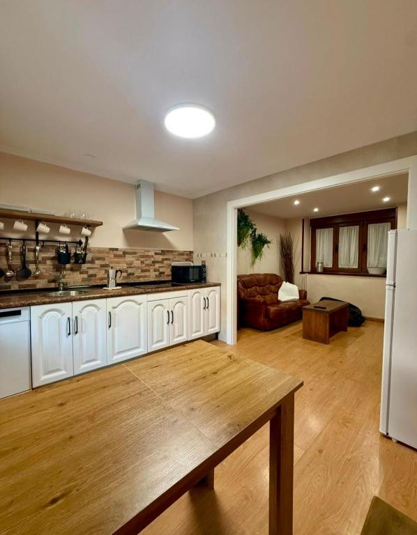 a large kitchen with white cabinets and a living room at La casina de isa in Aller