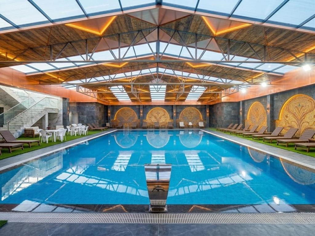 a large swimming pool with blue water in a building at Qorqud Hotel - Free Massage in Baku