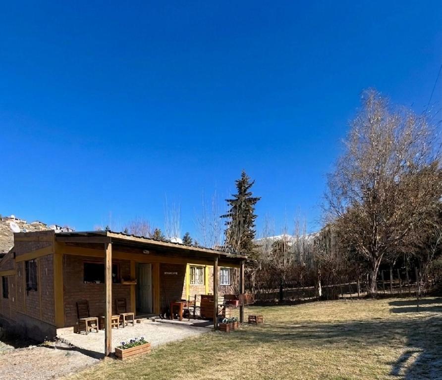 a small house in a field next to a forest at Potrerillos Nuestras Raíces in Potrerillos