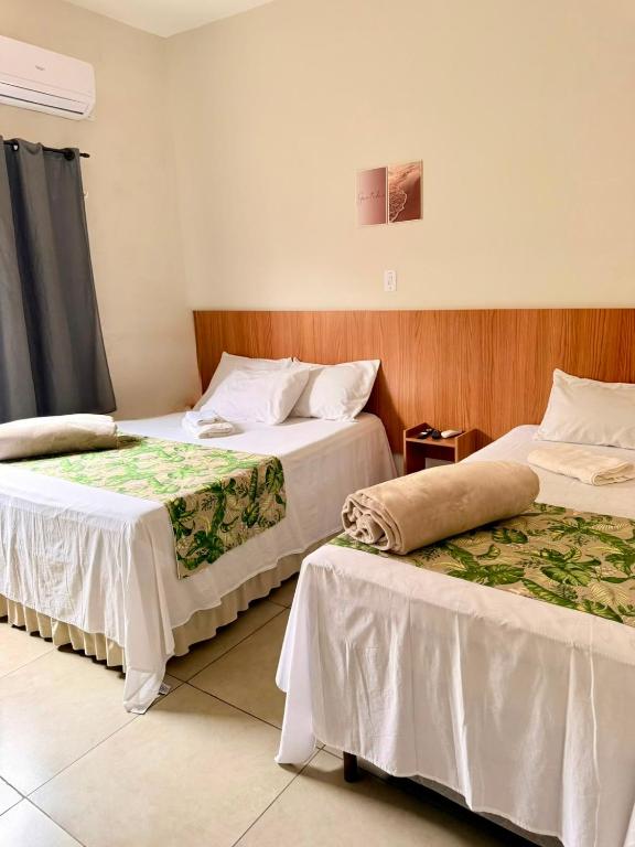 a hotel room with two beds and a window at Hotel Coutinho in Pirapora