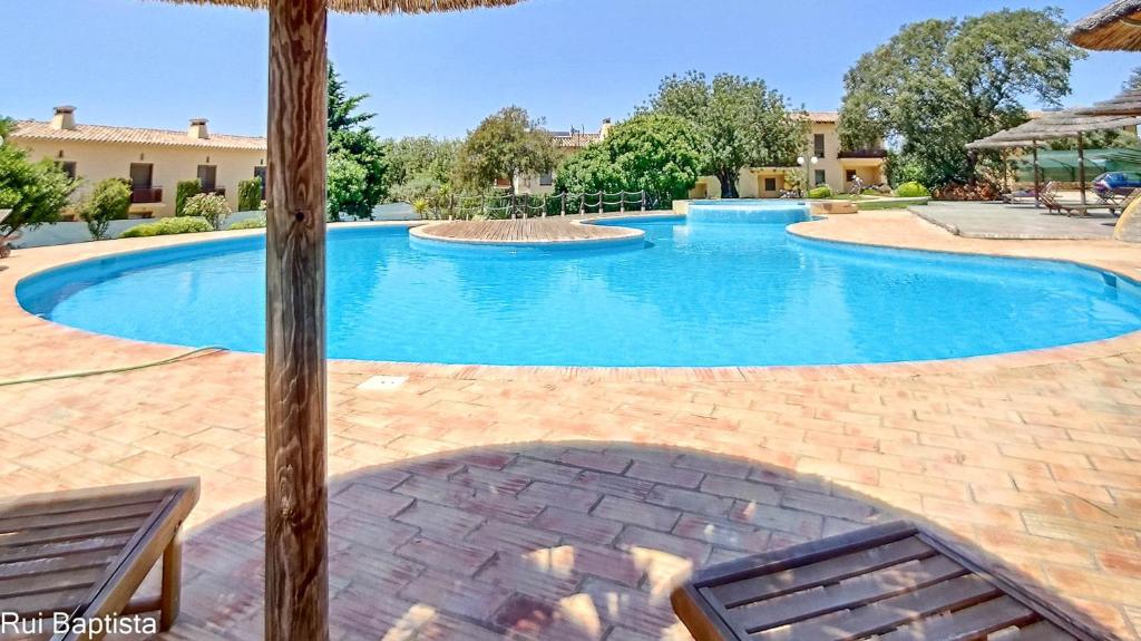 a large swimming pool with two chairs and an umbrella at Arrancada 7 in São Lourenço