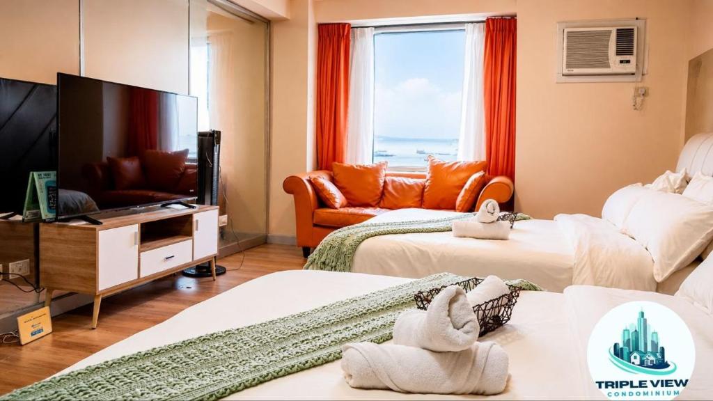 a living room with two beds and a flat screen tv at Tripleview luxurious eton baypark manila in Manila