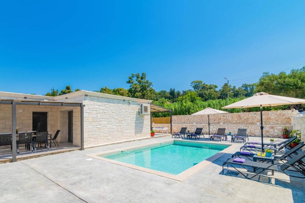 a swimming pool with chairs and an umbrella at Villa Casa Liveris by Villa Plus in Akrotiri