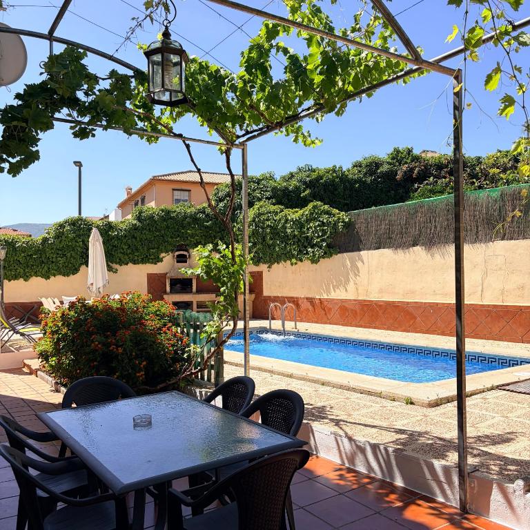 a patio with a table and chairs and a swimming pool at El Chalete in Otura