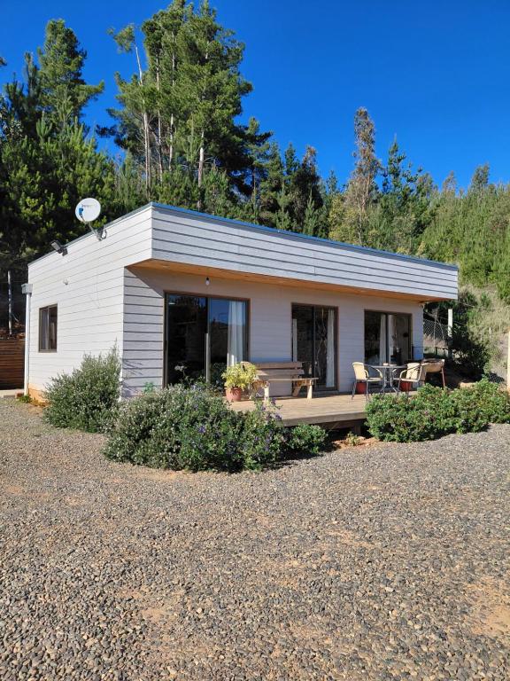 a small white cottage with a porch and chairs at Cabaña gam.nav in Vichuquén