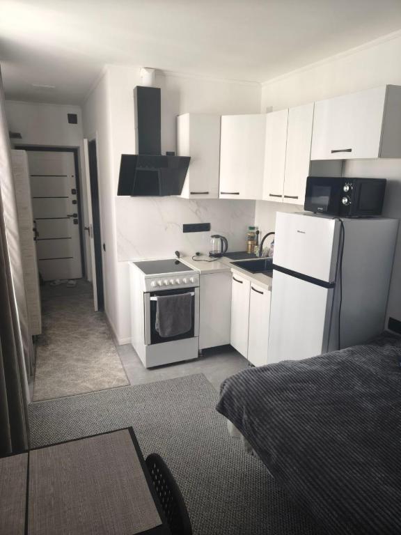 a kitchen with white cabinets and a stove and refrigerator at Квартира- студия in Chişinău
