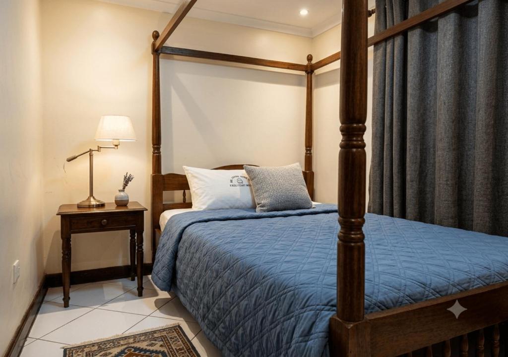 a bedroom with a canopy bed with a blue comforter at New Swanga in Nairobi