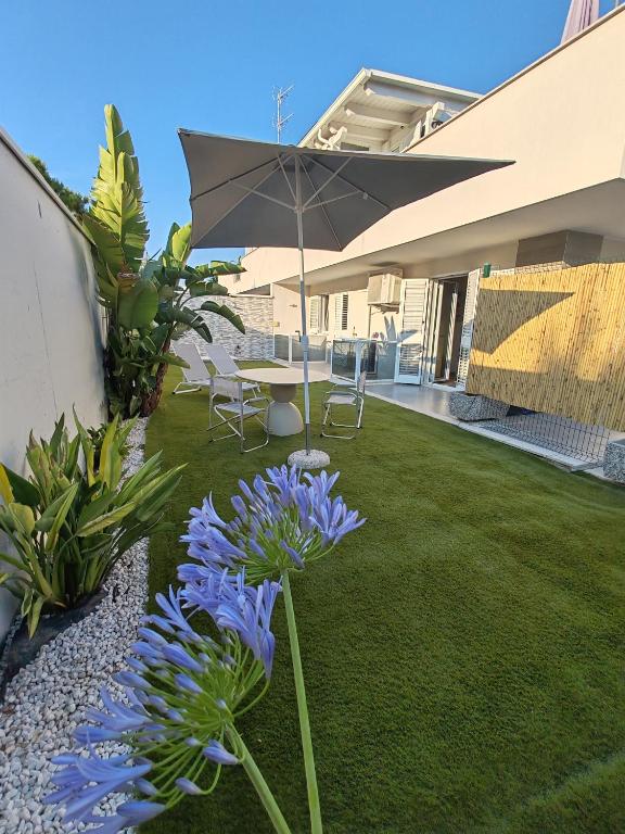 a garden with purple flowers and an umbrella at Villa Baia dei Gruccioni in Trani