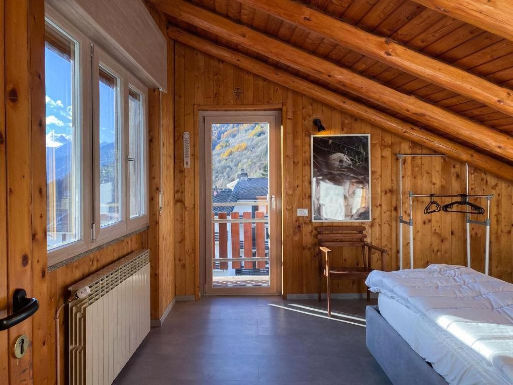 ein Schlafzimmer mit einem Bett in einem Zimmer mit Fenstern in der Unterkunft Panorama 3B - AffittiPontediLegno in Temù