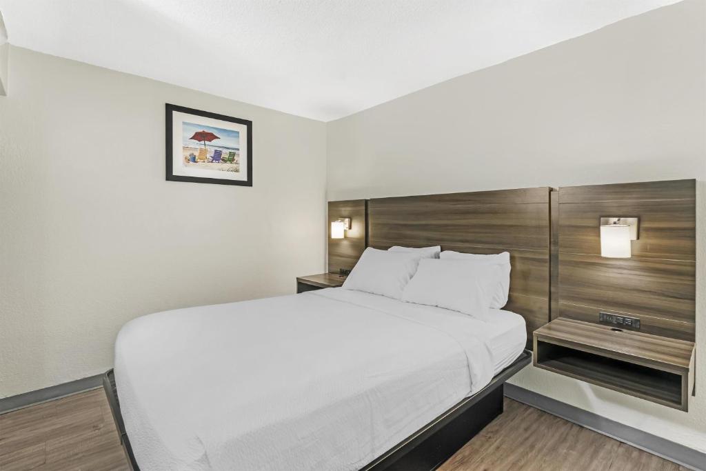 a bedroom with a large white bed with a wooden headboard at SureStay Studio by Best Western Virginia Beach Oceanfront in Virginia Beach