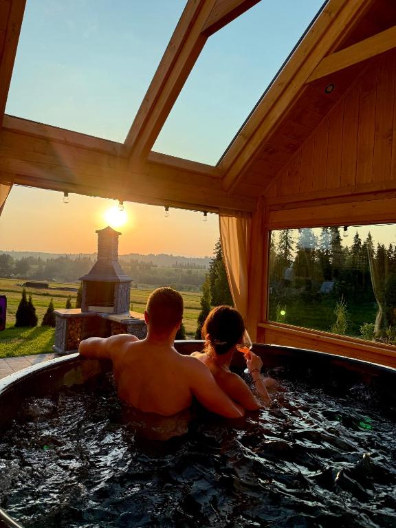 a man and a woman sitting in a hot tub at Apartament Bioło Izba in Czerwienne