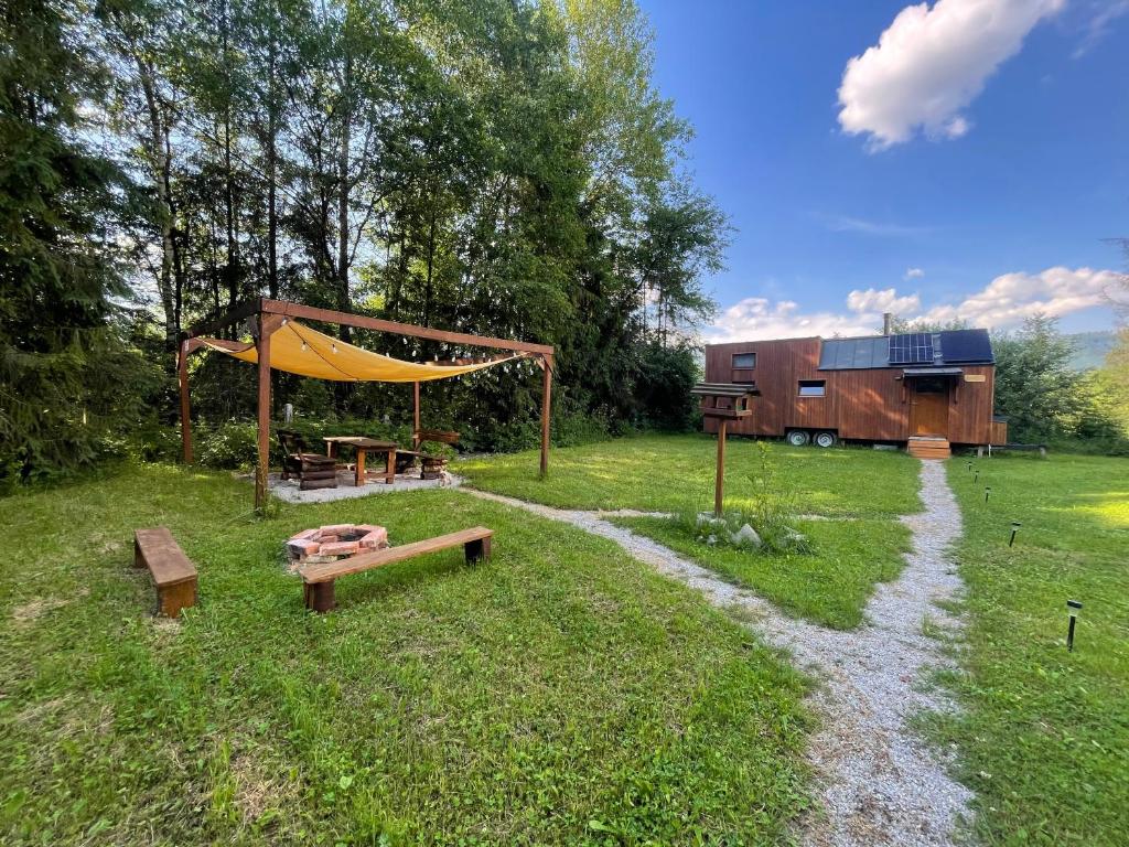 a tent and benches in a field with a barn at koliBka - tiny house in Michalová