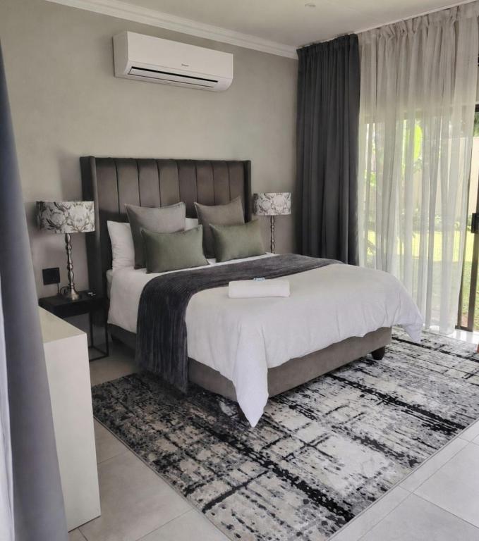 a bedroom with a large bed and a large window at F'leur Guesthouse in Mokopane