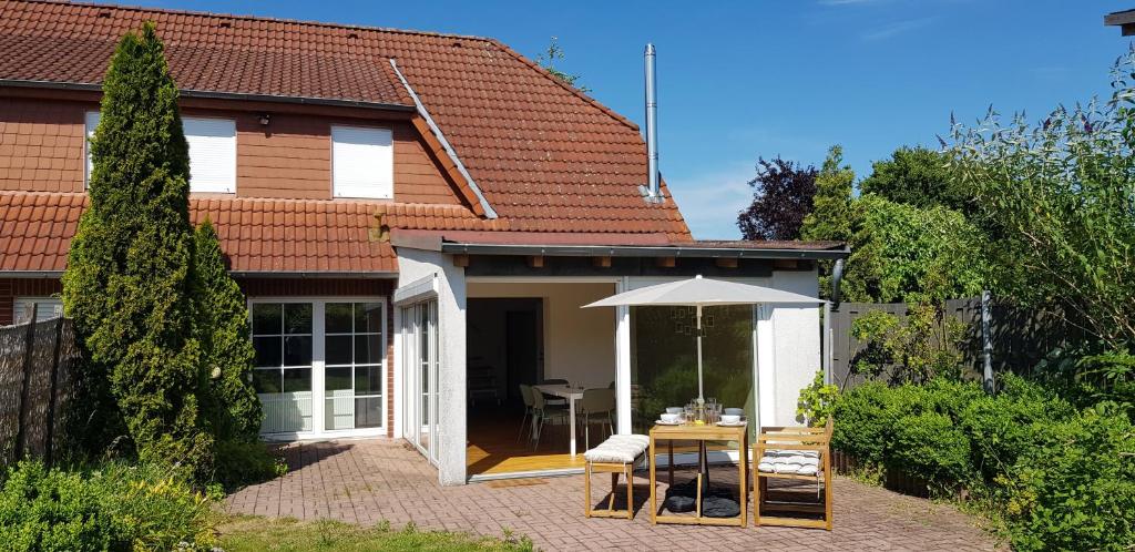 a house with a table and an umbrella at Fewo Mandelsloh in Neustadt am Rübenberge