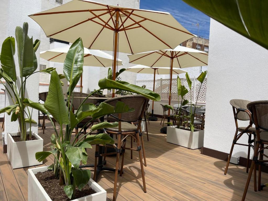 a patio with tables and chairs with umbrellas and plants at La Boutique Puerta Osario in Córdoba