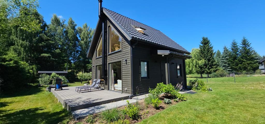 a black tiny house with a wooden deck at Murawki Dom Blisko Jeziora in Urowo
