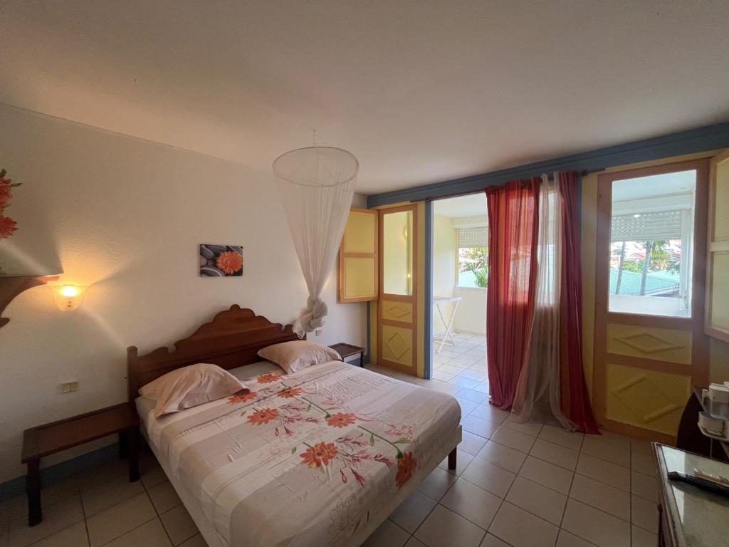 a bedroom with a bed with a chandelier at APPARTEMENT AMARYLLIS 2 à 3 min de la PLAGE Pointe Marin in Sainte-Anne