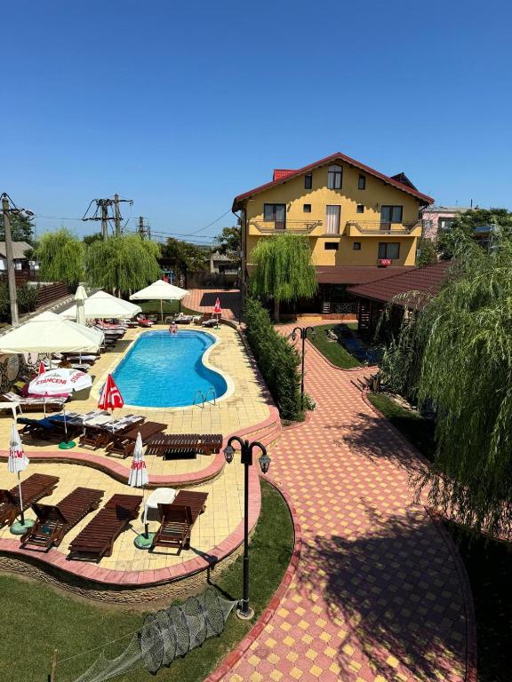 a resort with a swimming pool with chairs and umbrellas at Pensiunea Bianca in Murighiol