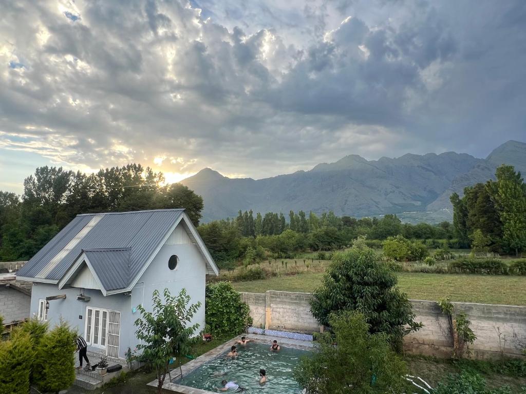 a white house with a swimming pool in a field at The Forest Way Loft by YEMBERZAL in Srinagar