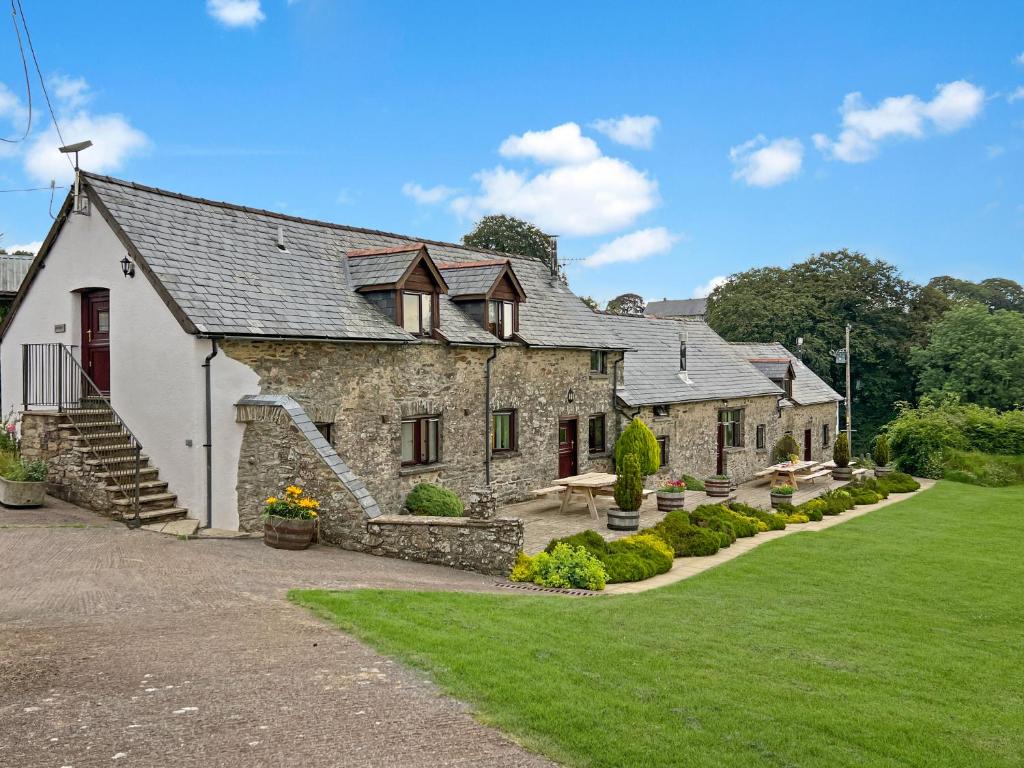 an old stone house with a lawn in front of it at Jasper Cottage Hawkridge in Dulverton