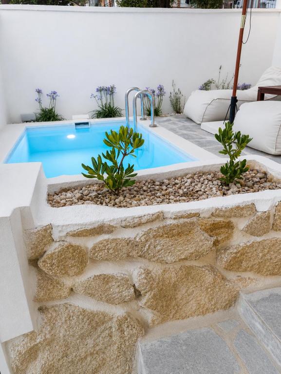 a swimming pool in a backyard with a rock retaining wall at Ιόνια Γαλήνη Pool Spa Suite in Parga