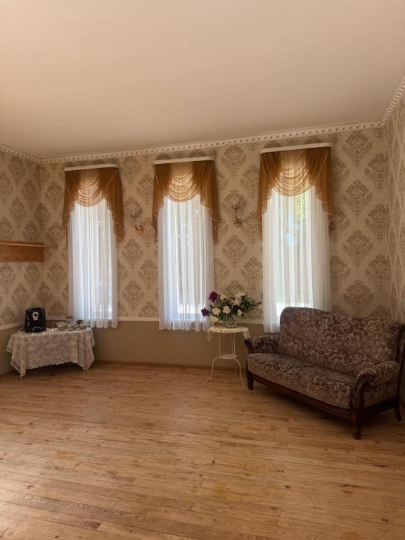 a living room with a couch and two windows at Leču muiža in Lēči