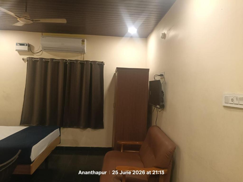 a room with a bed and a chair and a window at Vybhav Residency AC in Anantapur
