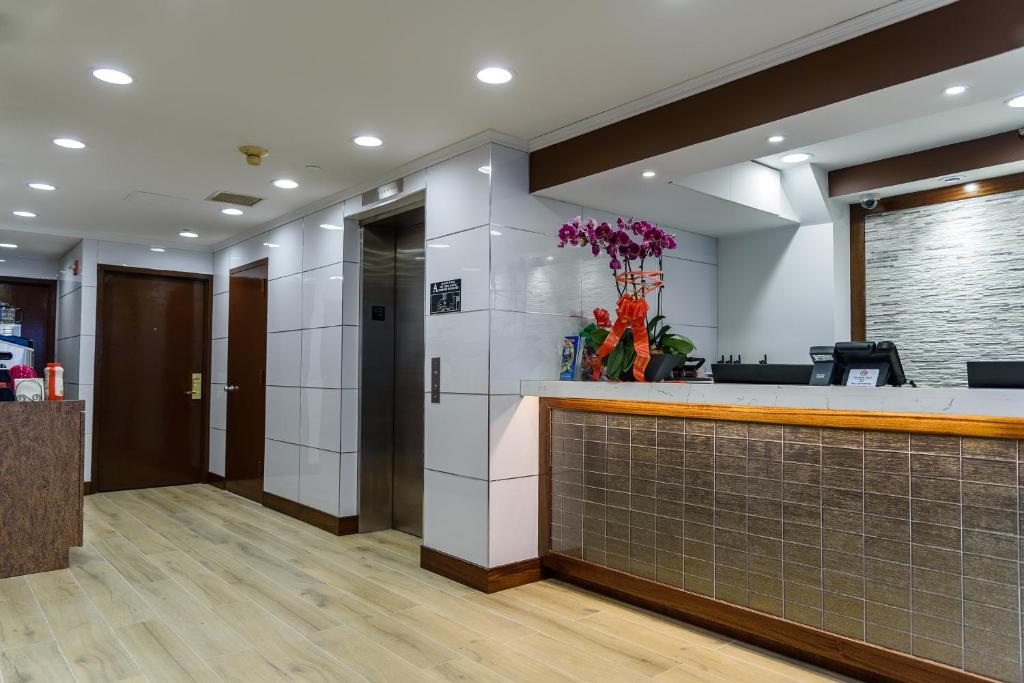 an office lobby with a reception counter and flowers at Flushing Central Hotel in Queens