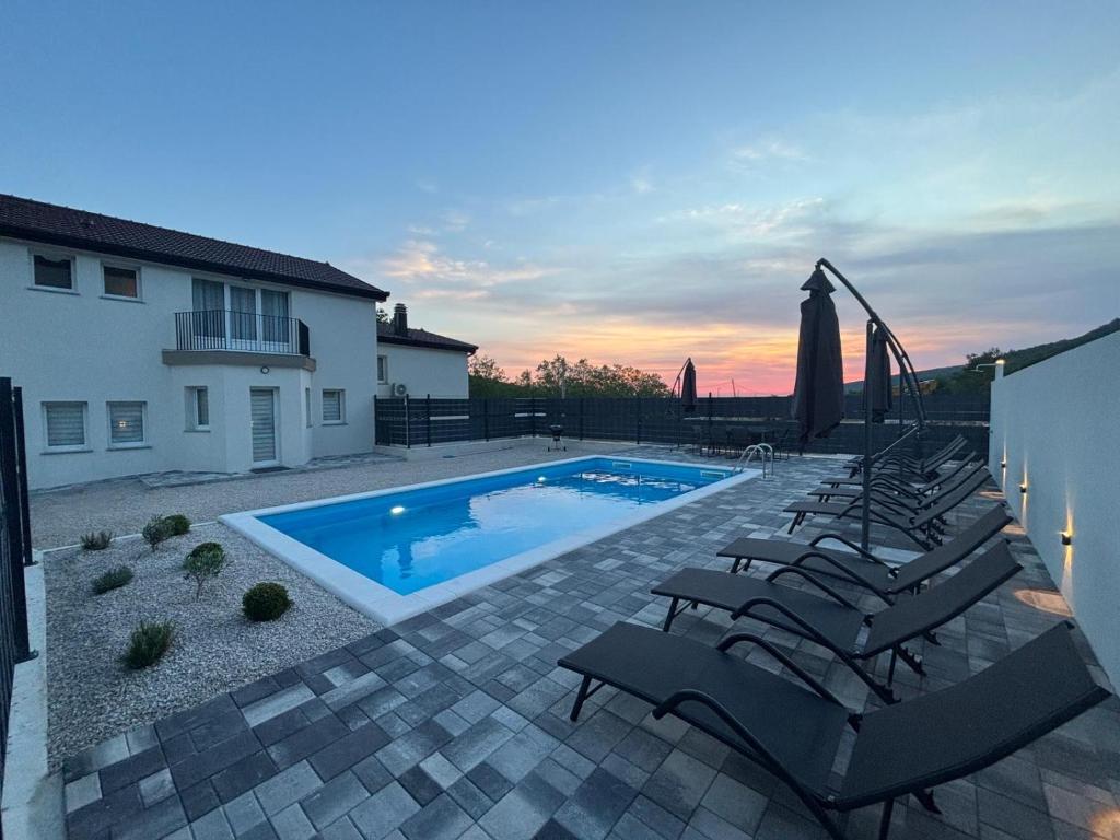 a swimming pool with lounge chairs next to a house at Villa Imvelo Lovrec - Spacious Villa With Private Pool in Lovreć