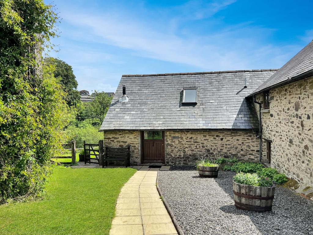 a stone house with a door and a pathway at Smiddy Cottage Hawkridge in Dulverton