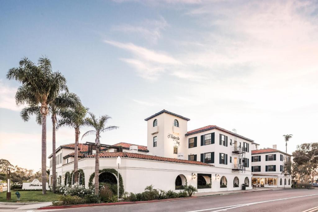 a white building with palm trees on a street at Montecito Inn in Santa Barbara