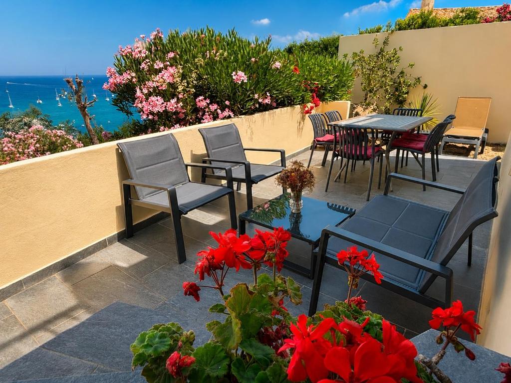 a patio with tables and chairs and red flowers at APPARTEMENT TERRASSE La Citadelle Appartements Saint Florent in Saint-Florent