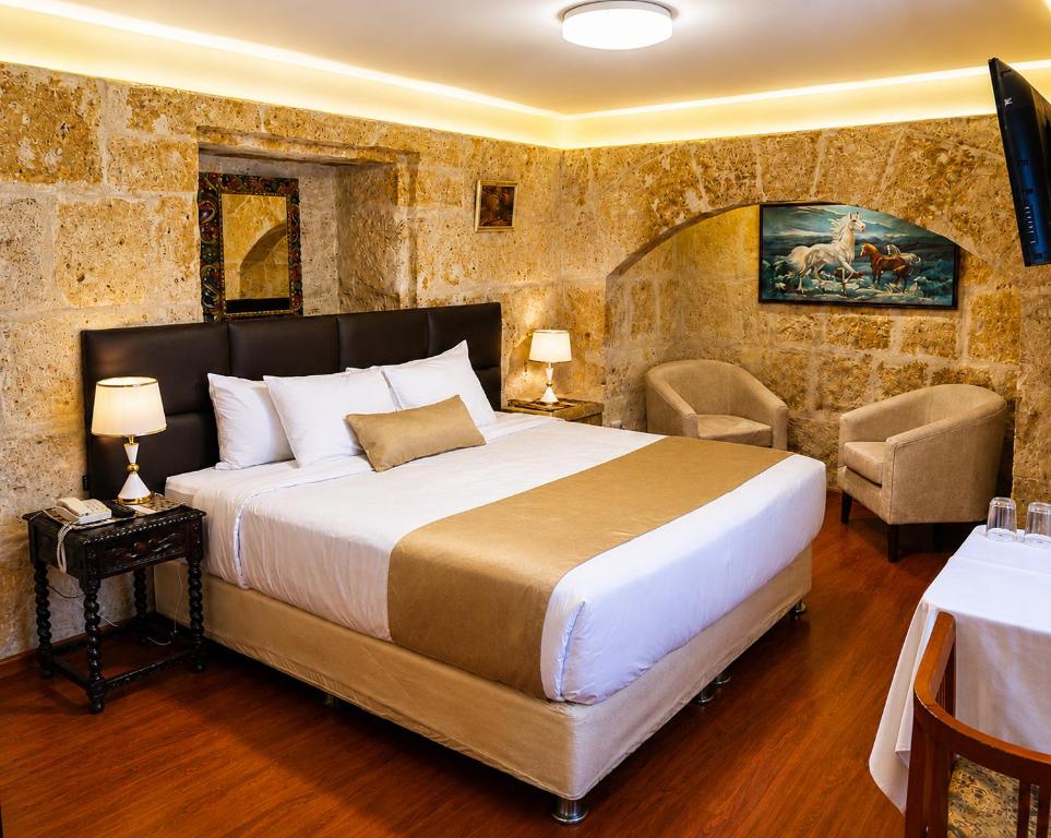 a bedroom with a large bed and two chairs at Hotel Santa Rosa in Arequipa