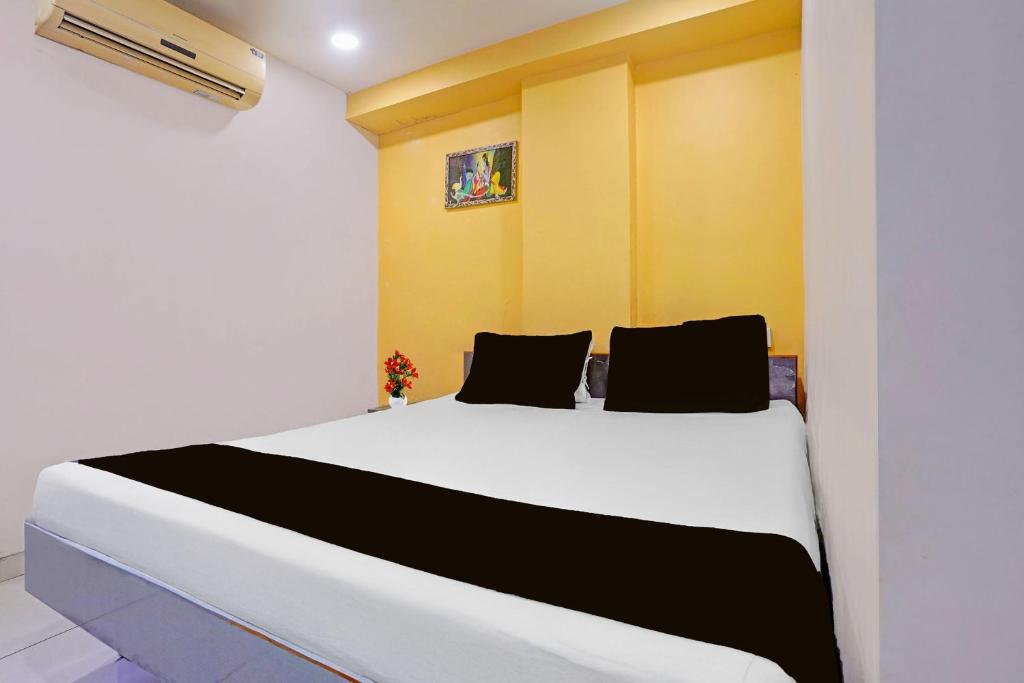 a bedroom with a white bed with black and yellow walls at Hotel O Unity Guest House in Dabhoi