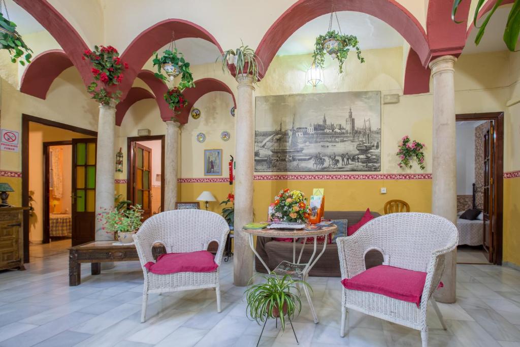 sala de estar con 2 sillas y mesa con cojines rosas en Pensión Javier en Sevilla